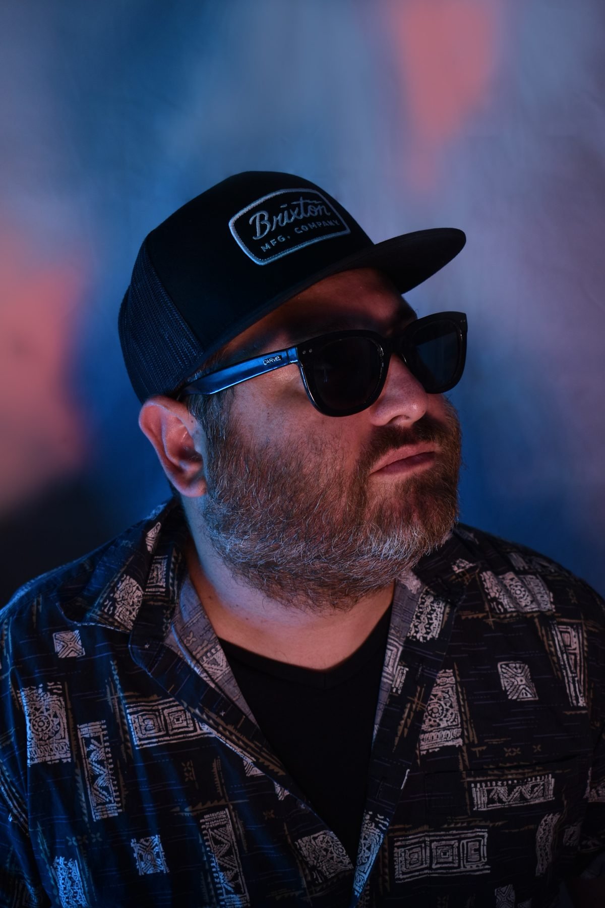 Hans Nüsslock in a Brixton cap and sunglasses under blue and pink light