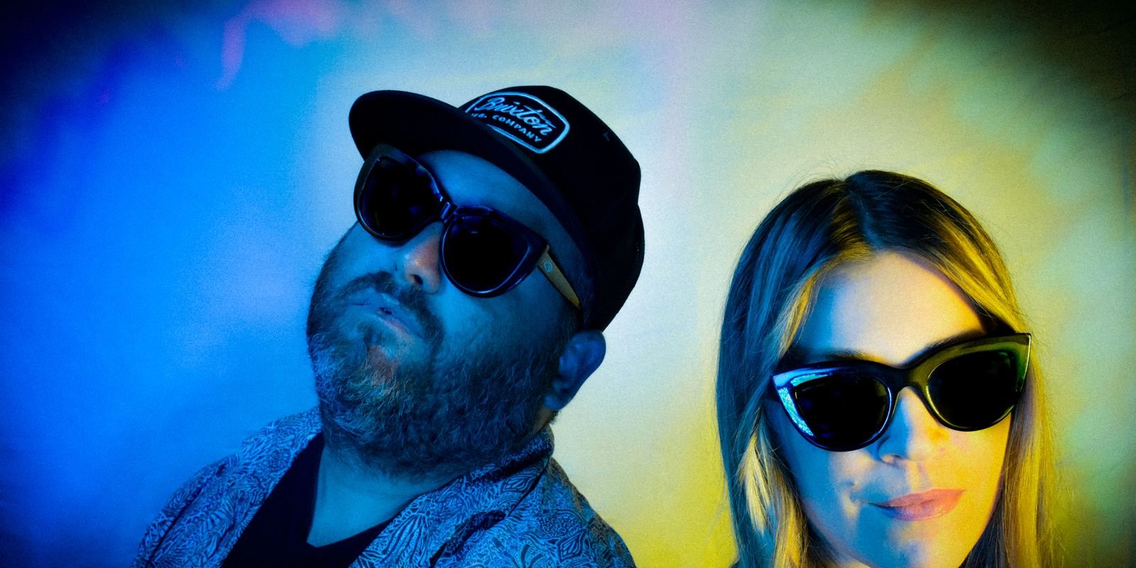 Hans and Jeanna in sunglasses under blue and yellow light
